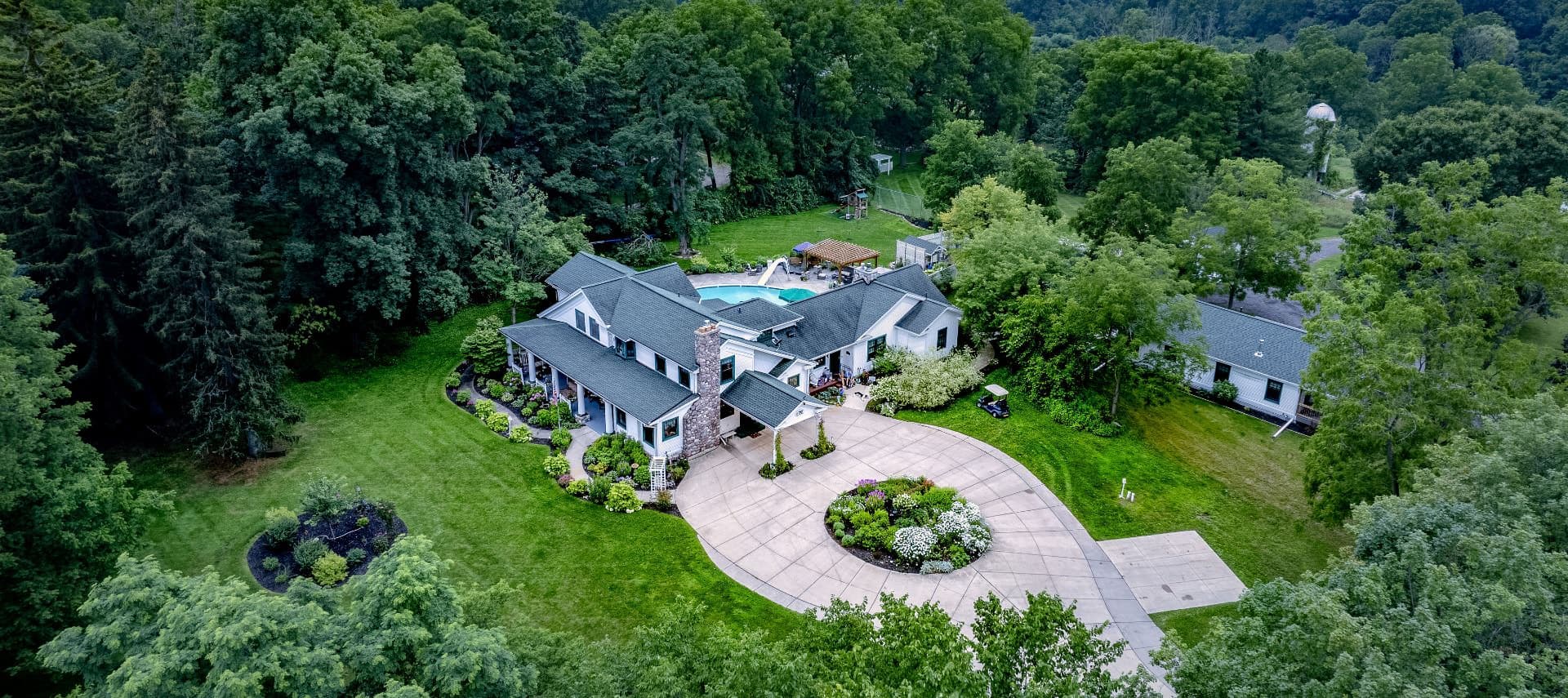 Aerial view of a large, landscaped home with a pool surrounded by trees. Aerial view of a large, landscaped home with a pool surrounded by trees.