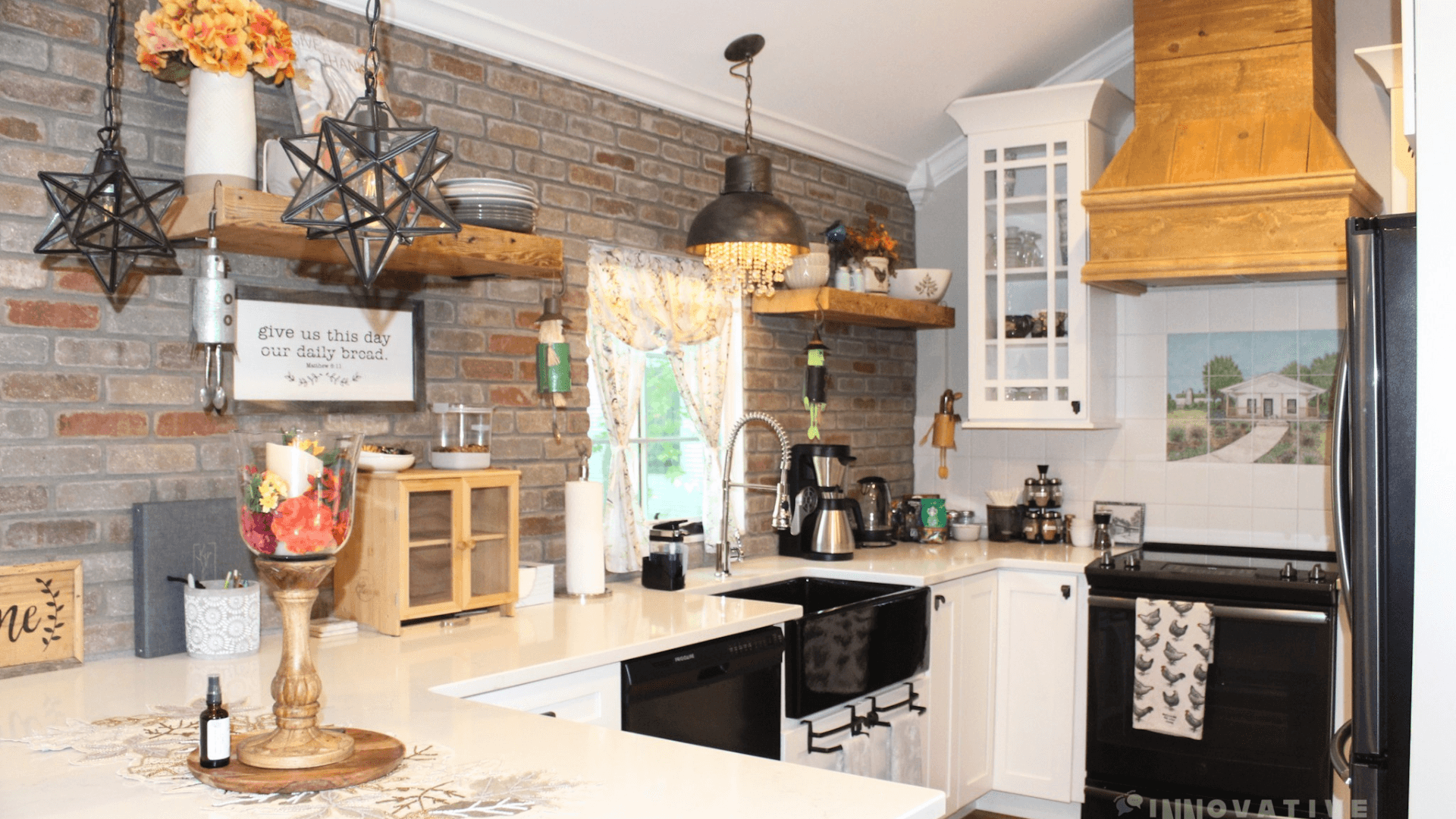 A modern kitchen with brick walls, white cabinetry, and rustic decor.